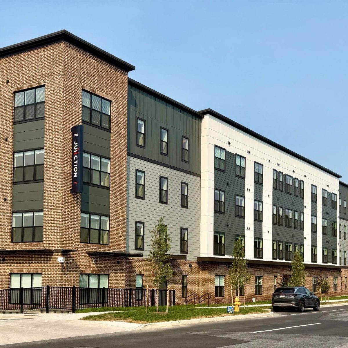 Multi-story apartment building with brick and green siding, The Junction signage on corner tower