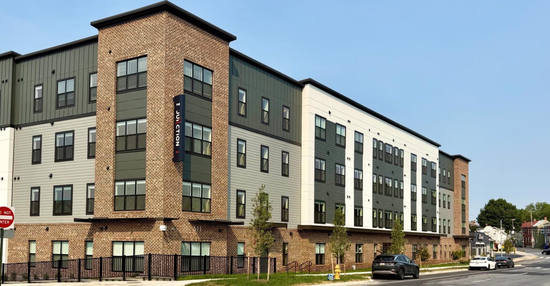 Multi-story apartment building with brick and green siding, The Junction signage on corner tower