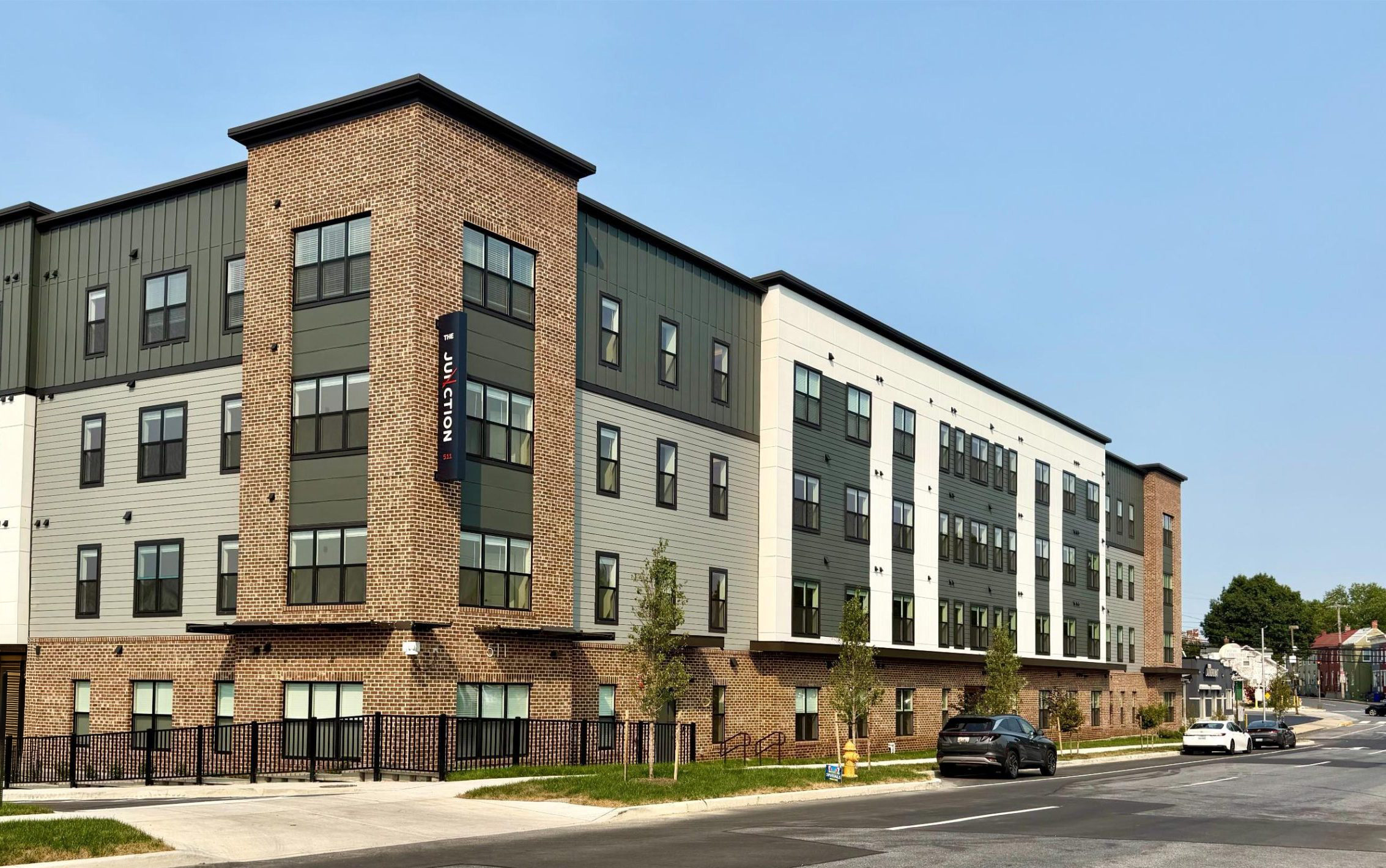 Multi-story apartment building with brick and green paneled exterior featuring The Junction signage on the corner tower