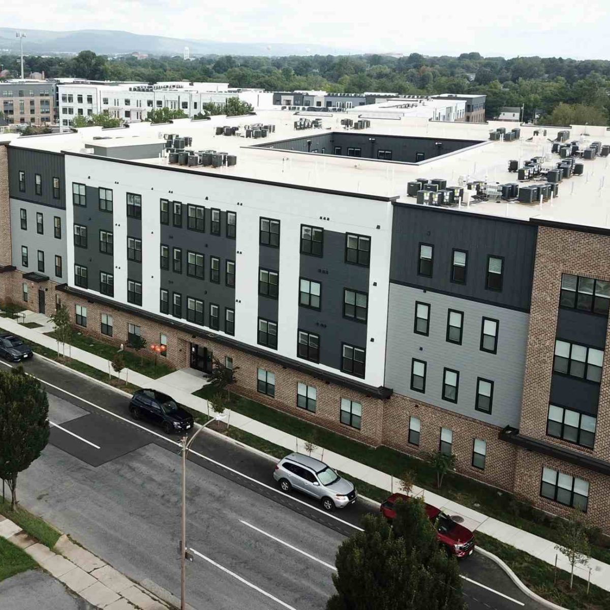 Aerial view of The Junction apartment building exterior with brick and gray siding along a tree-lined street in Frederick, MD