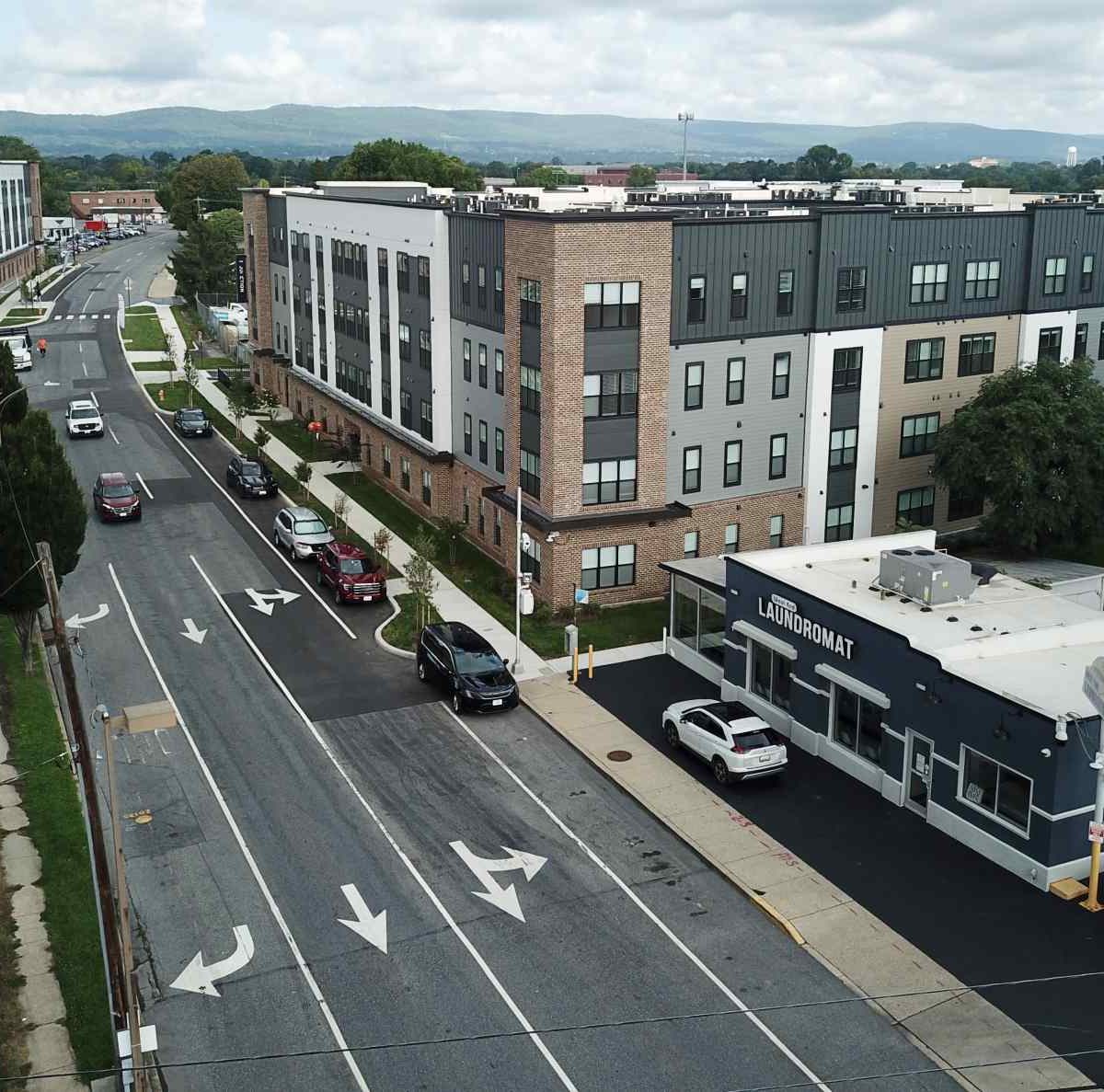 Aerial view of The Junction apartment complex with a laundromat and parking lots along a tree-lined street in Frederick, MD.