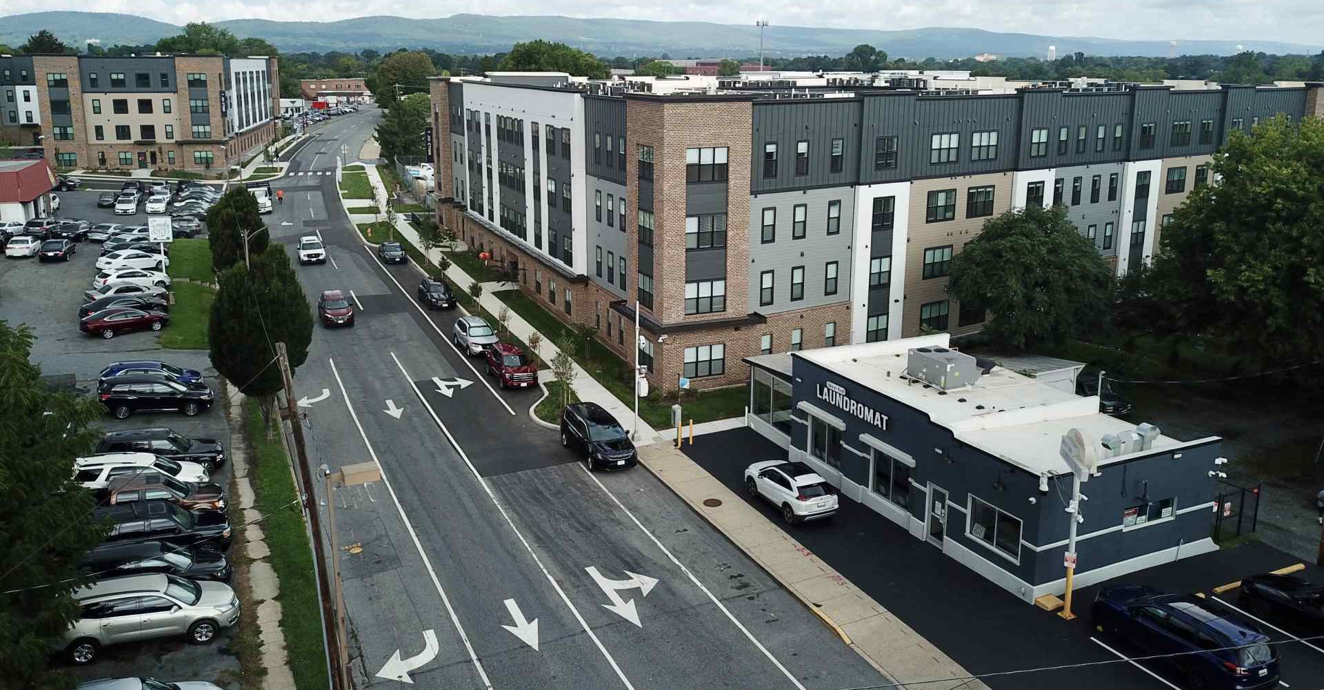 Aerial view of The Junction apartment complex with a laundromat and parking lots along a tree-lined street in Frederick, MD.