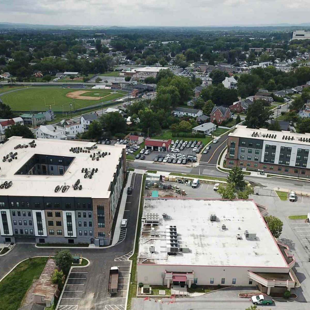 Aerial view of The Junction apartment buildings with courtyard and parking amid a residential neighborhood with a ballfield nearby