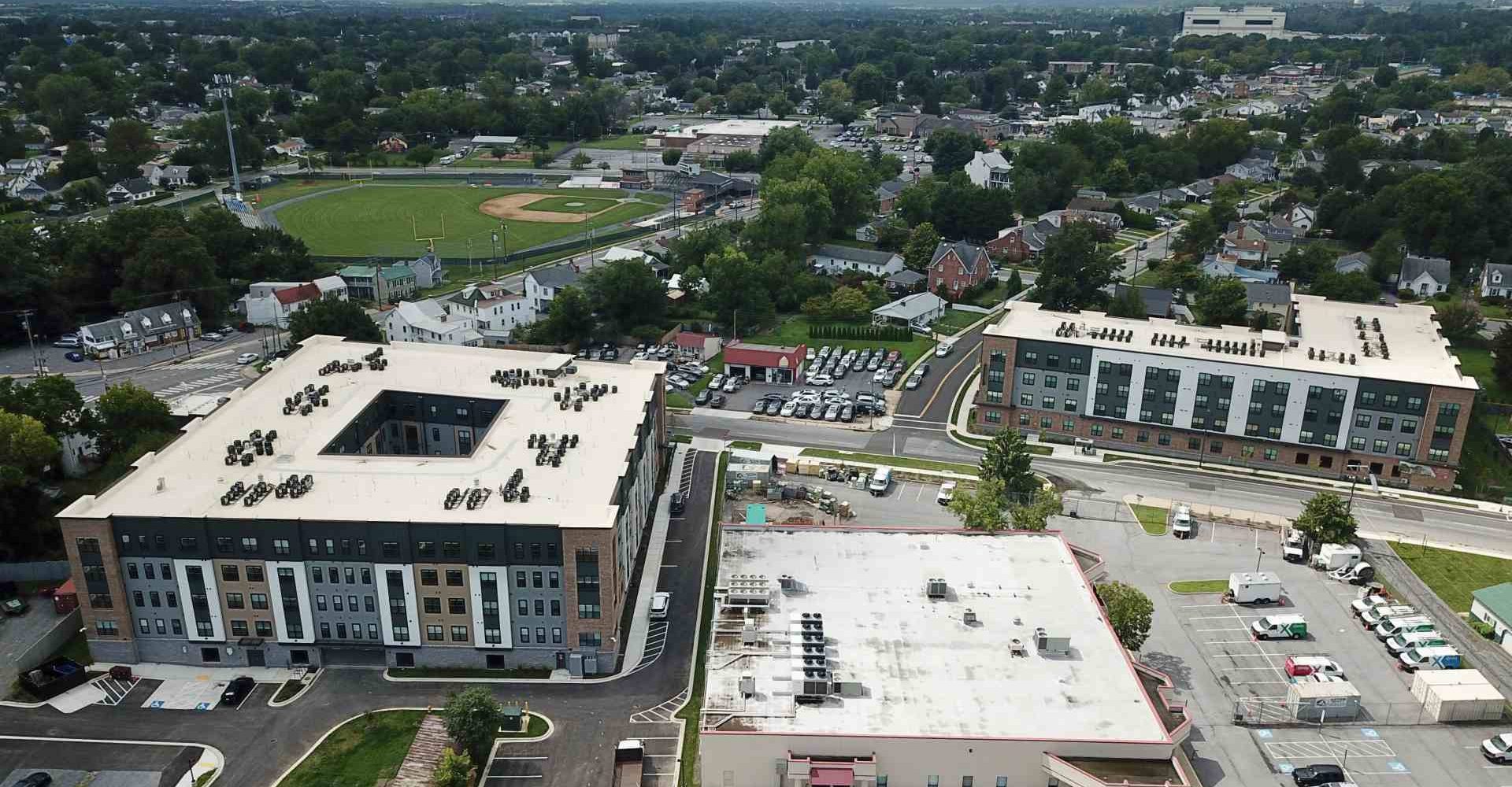 Aerial view of The Junction apartment buildings with courtyard and parking amid a residential neighborhood with a ballfield nearby