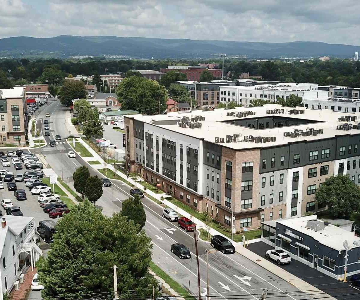 Aerial view of The Junction apartment complex in Frederick, MD, surrounded by streets, parking, and mountains in the distance.